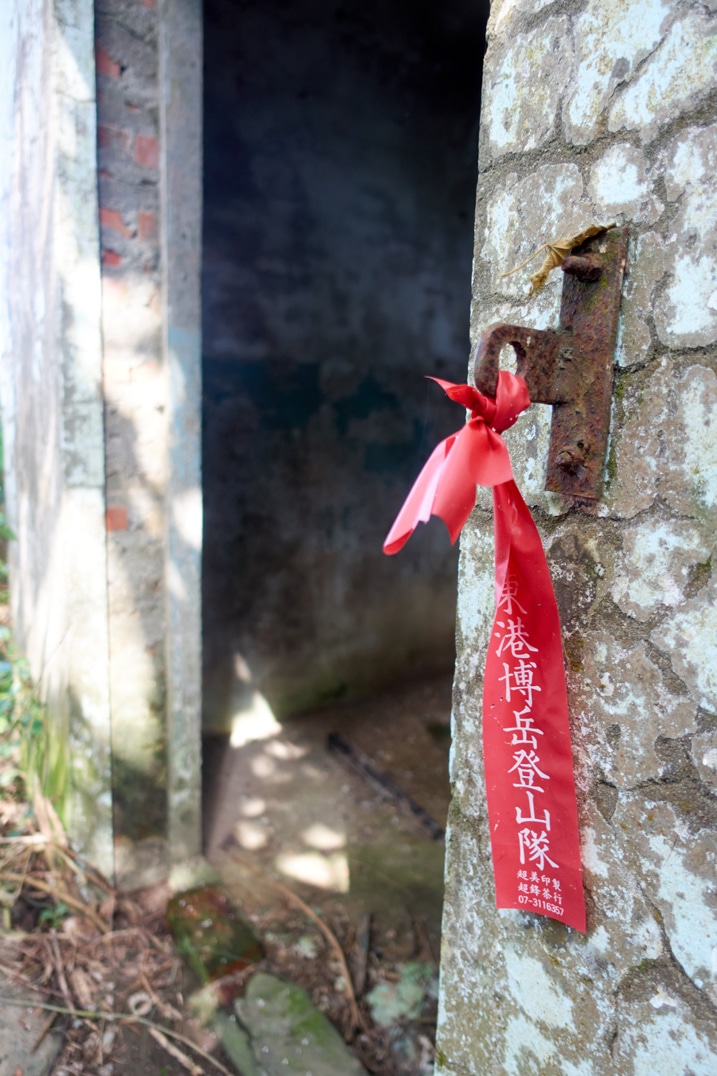 Red ribbon with Chinese writing on it attached to metal door hook - doorway - concrete building