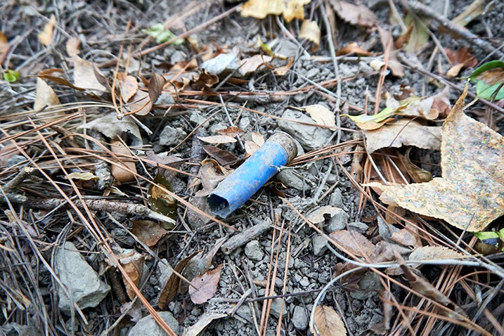 Blue colored used shotgun shell on the ground