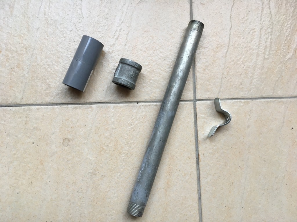 Metal pipe, pipe connector, pvc connector, and bent metal piece on tiled floor