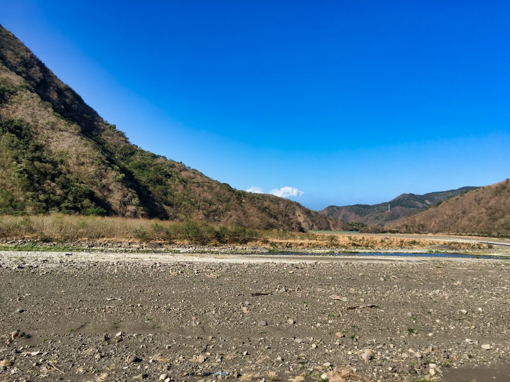 Mostly dry riverbed - watermelons planted - mountains and blue sky