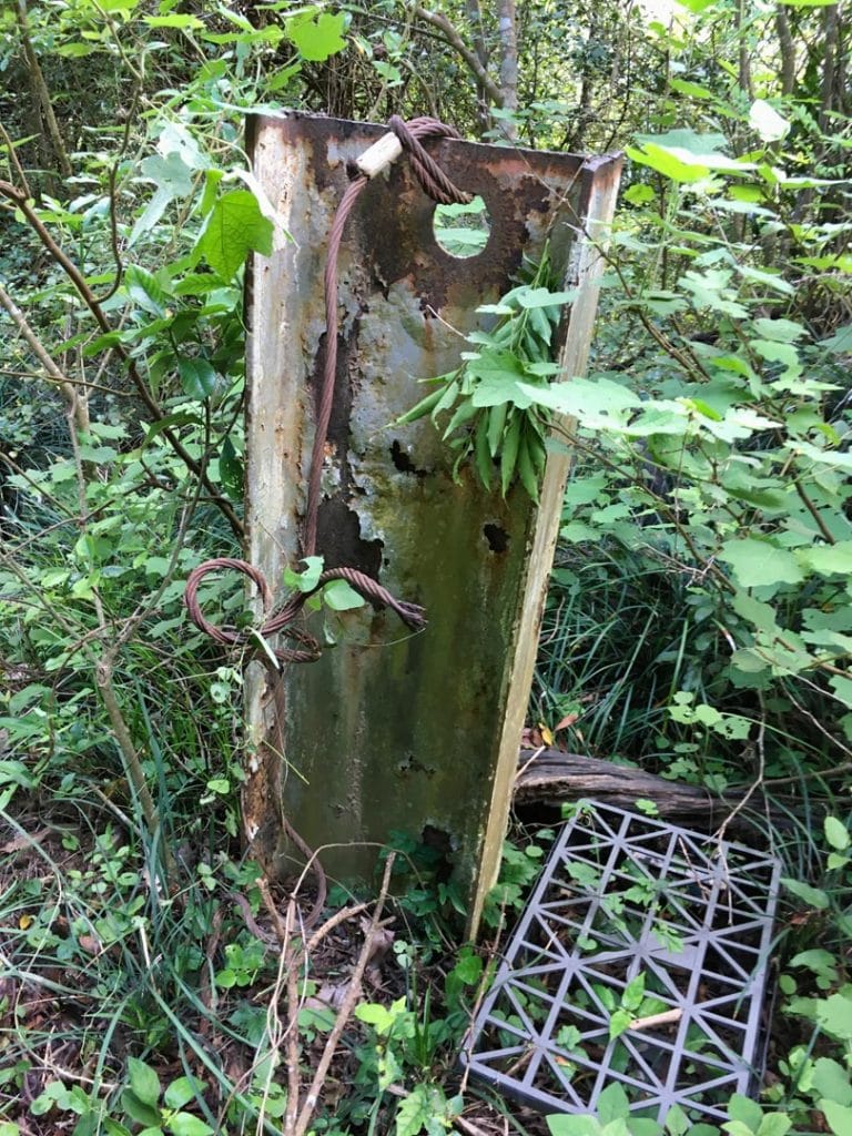 Metal beam stick out from ground - old plastic rat trap next to it