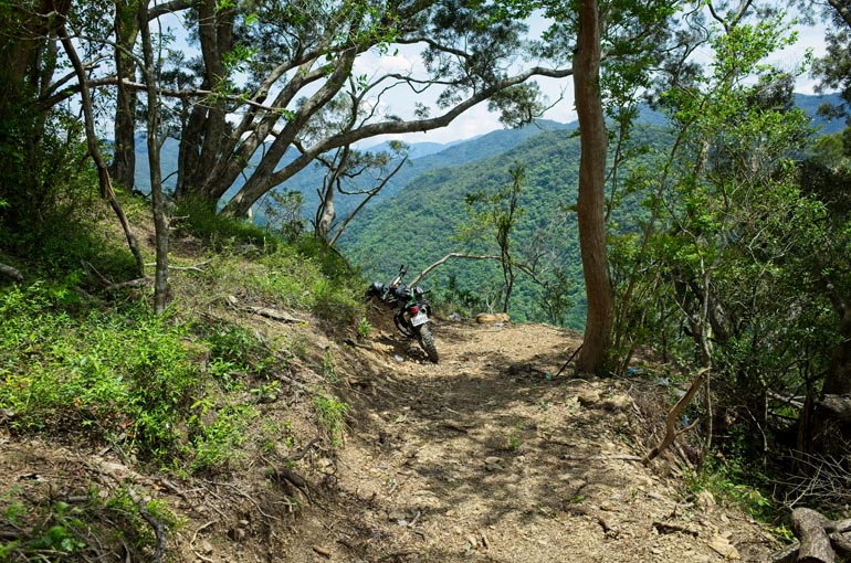 Mountain trail ending suddenly - motorcycle parked near edge