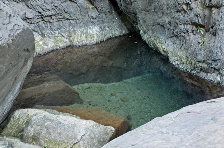 Small pool of deep water surrounded by boulders 