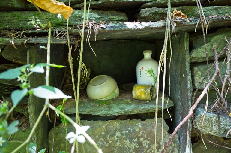 Altar within stone foundation - bowls, candle and decorated vase or bottle inside