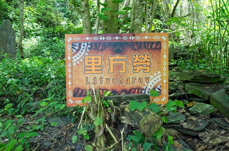 An orange sign with the name Ljivangrav printed on it - attached to tree - near foundation rocks