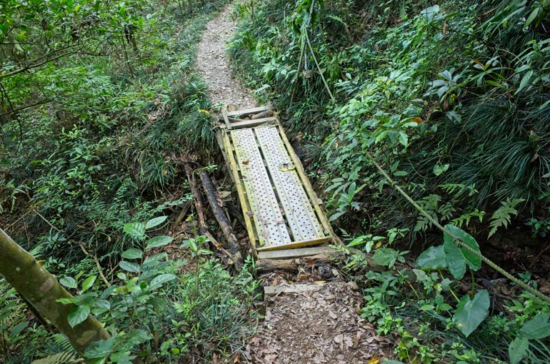 Some sort of metal grating used as a short bridge - rope to the right - trail continues past grating