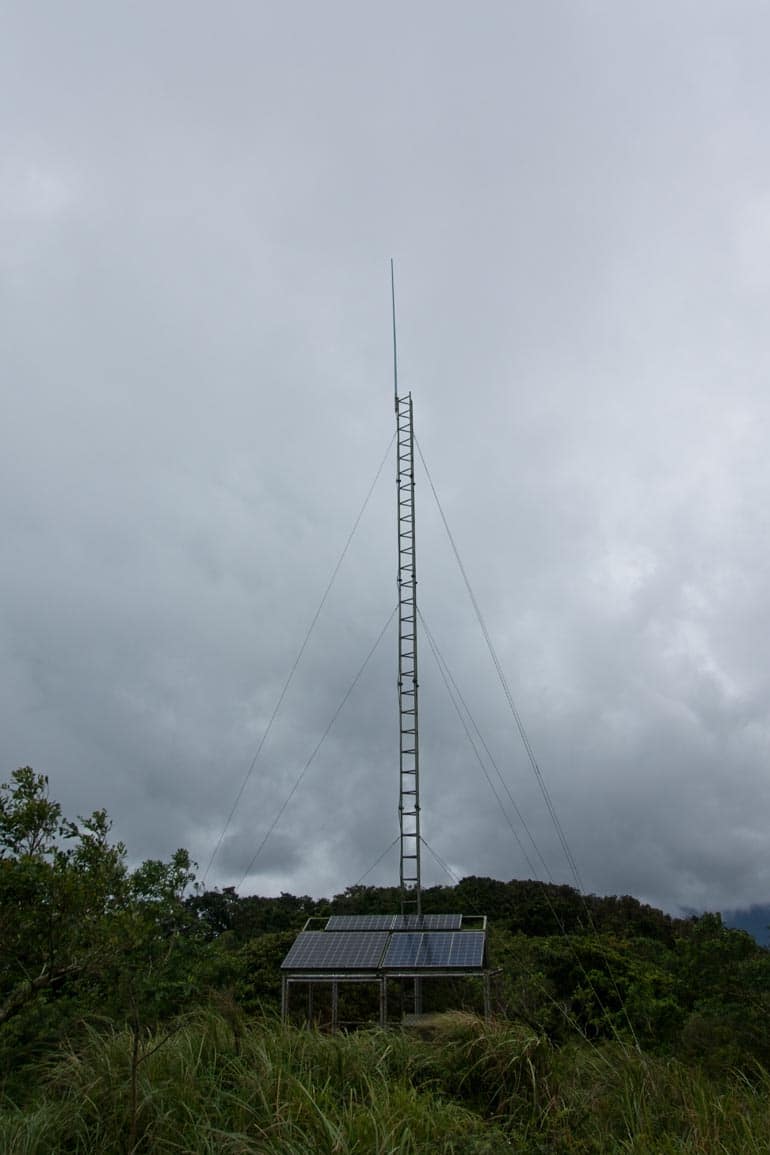 Antenna and fenced off area around it below from a distance - overcast skies above