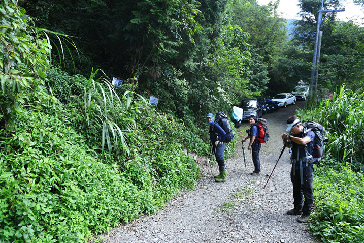 Hikers standing on road next to a trail head