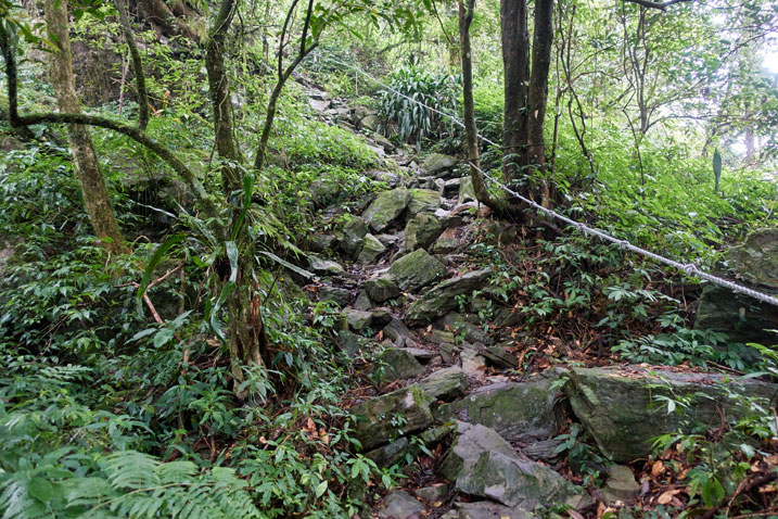 Rocky trail going up, with rope on right side