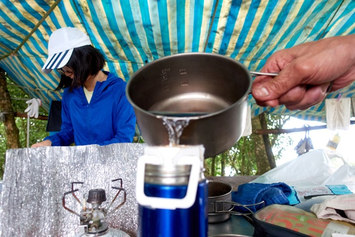 Water being poured into coffee bag into cup - girl standing in background