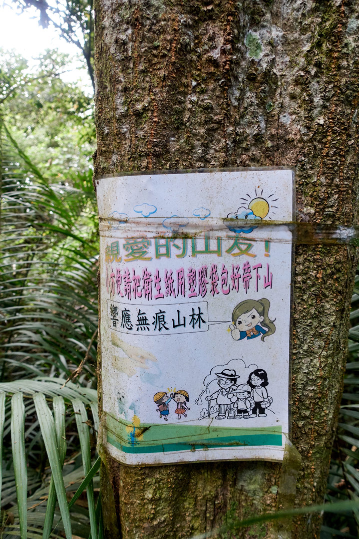 A sign in chinese attached to a tree - WeiLiaoShan 尾寮山 trail