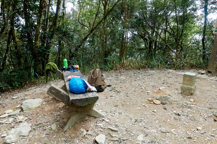 Open area with a small bench with gear on top and backpack nearby - WeiLiaoShan 尾寮山