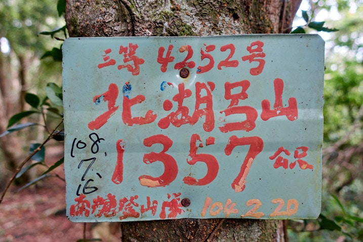 Faded green sign with red lettering in Chinese - BeiHuLuShan Peak 北湖呂山