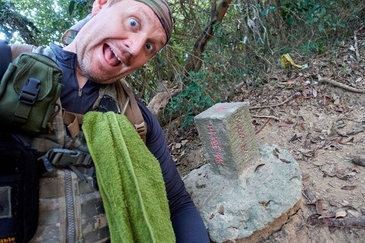 Man posing in front of survey stone for 北旗尾南山