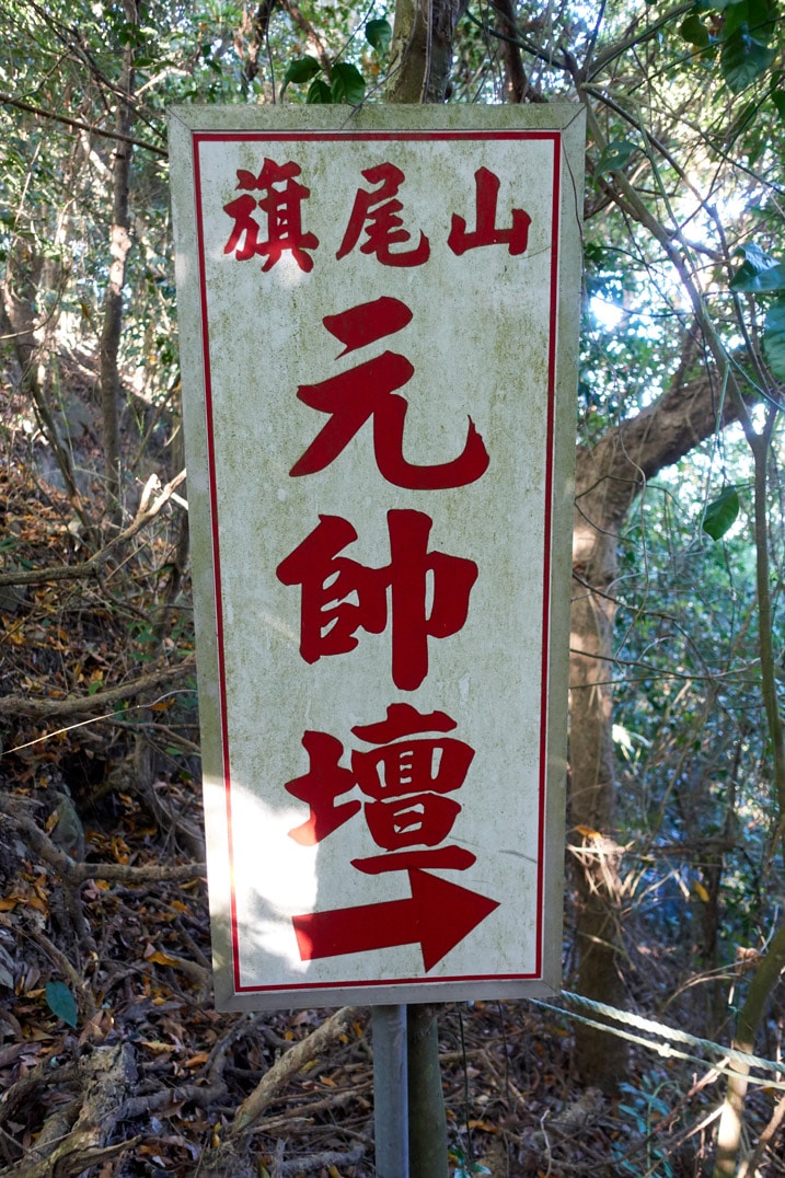 White and red sign written in Chinese attached to tree - 旗月縱走