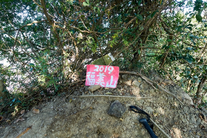 Red sign in Chinese lying on the ground next to hiking pole - 旗月縱走 - 福美山