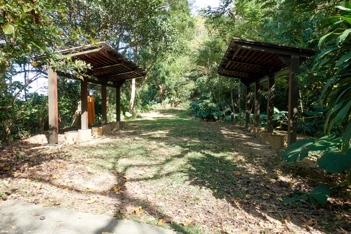 Open dirt and grass area with two covered sitting areas flanking it - 靈山步道 - 旗月縱走