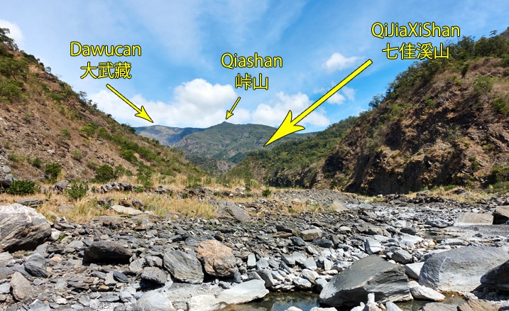 Rocky riverbed with mountain peaks labeled in English and Chinese