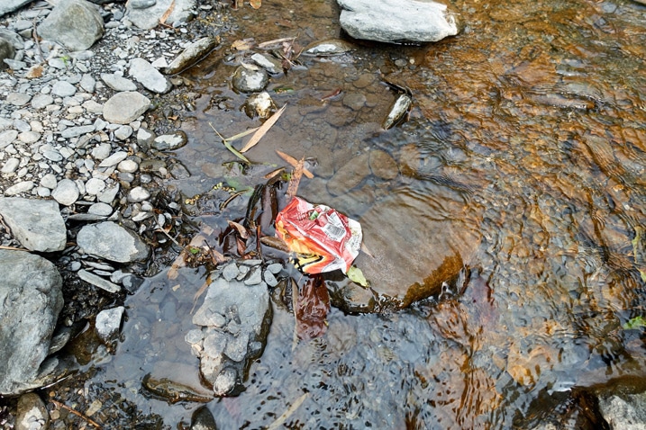 Empty bag of chips discarded in water on riverbed