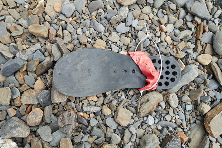 Sole of a boot lying on rocks with red electrical tape and zip ties around it
