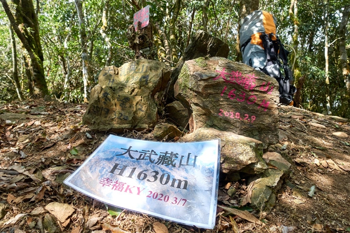 Large stones next to each other with Chinese writing on them - laminated sign with Chinese in front of stones - backpack in the background