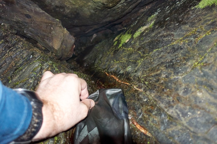 Water flowing down rocks - hand holding water bag - collecting water