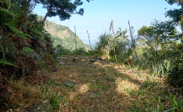 Mountainside hunter's camp - flat open area - mountains beyond - blue sky