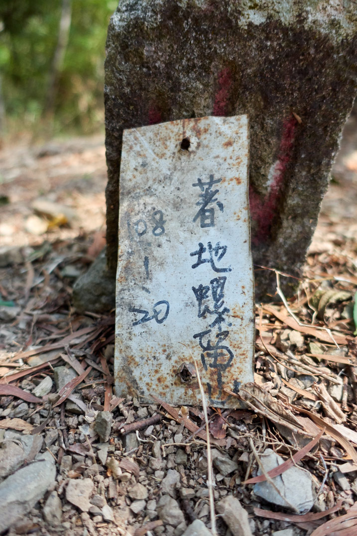 Small white metal sign with chinese writing on it - next to triangulation stone