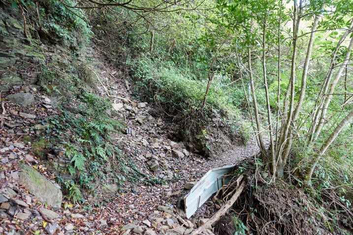 rocky dirt trail - small landslide patched up with corrugated metal