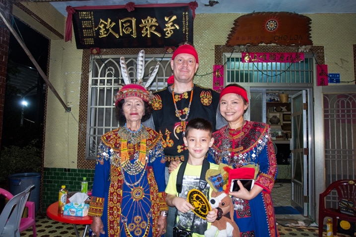 four people in Paiwan traditional clothing standing in front of house for picture