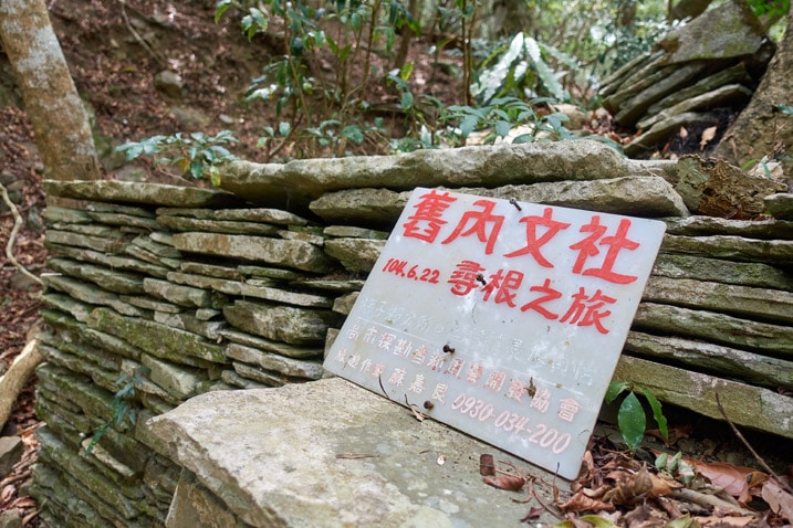 White sign with red chinese words printed o nit - stones stacked behind sign