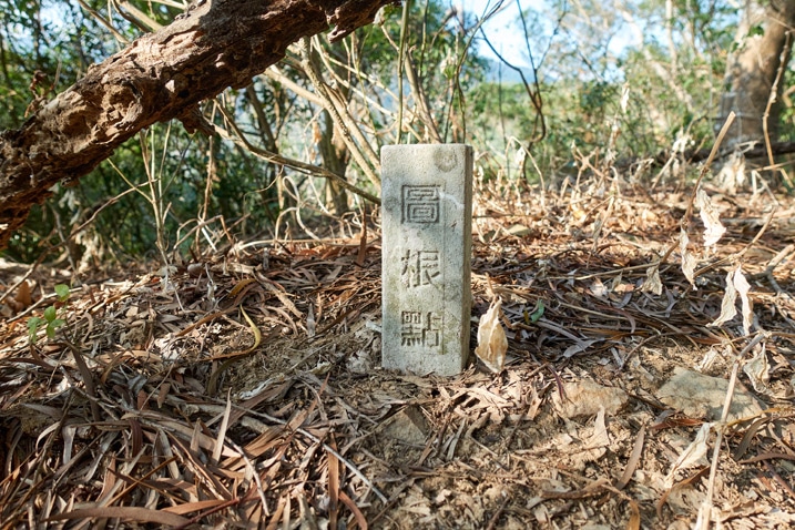 White stone marker in the ground with three Chinese characters written on it