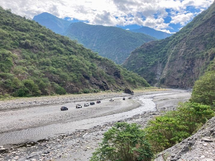 Convoy of 4x4 vehicles on wide riverbed - mountains in distance