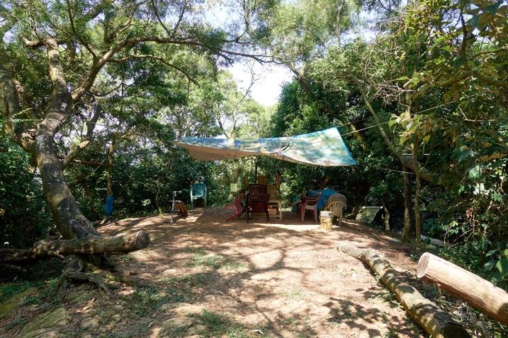 Cleared dirt area in mountains with table, chairs and tarp