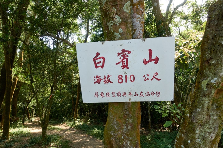 White sign attached to tree with Triangulation stone of 白賓山 written on it