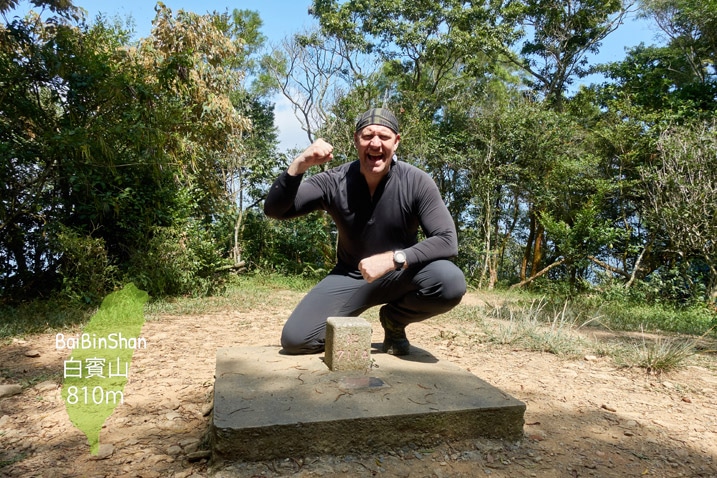 Man kneeling triumphantly behind triangulation stone