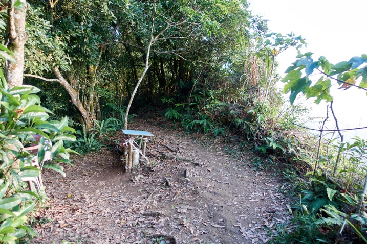 Open dirt area on mountain ridge with chairs and table - trees all around