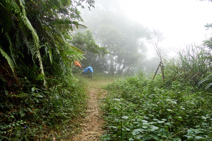 Dirt path in mountain jungle - foggy - motorcycle parked in distance