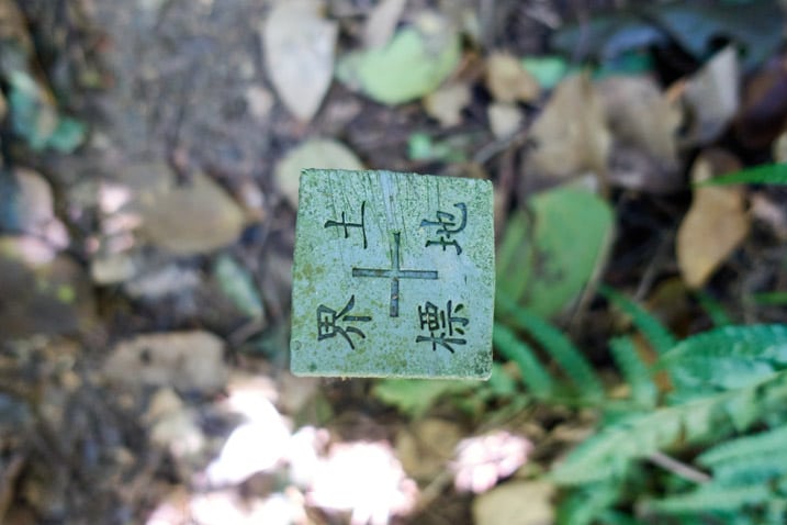 Closeup of top of plastic marker next to trail - square shape - Chinese writing on it