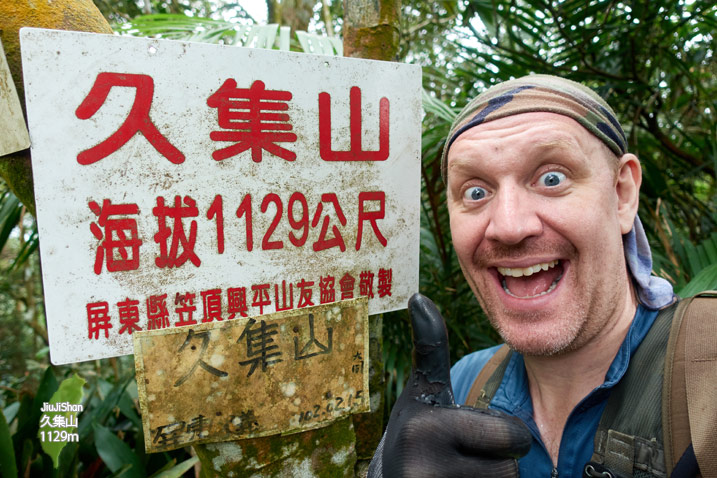 Jiujishan - 久集山 Peak - Man next to sign with happy look on his face