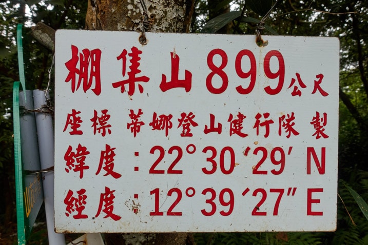 Closeup of white sign with red chinese words attached to a tree