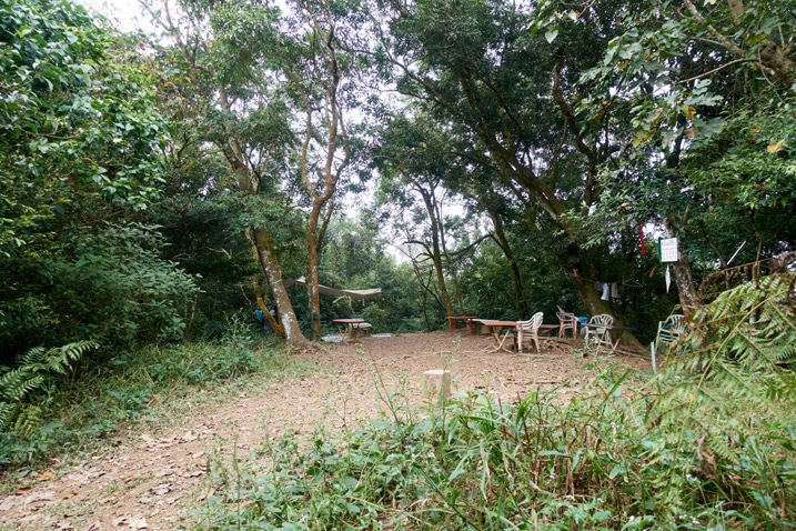 Open dirt area - chairs and tables all around - many trees in background - PengJiShan - 棚集山