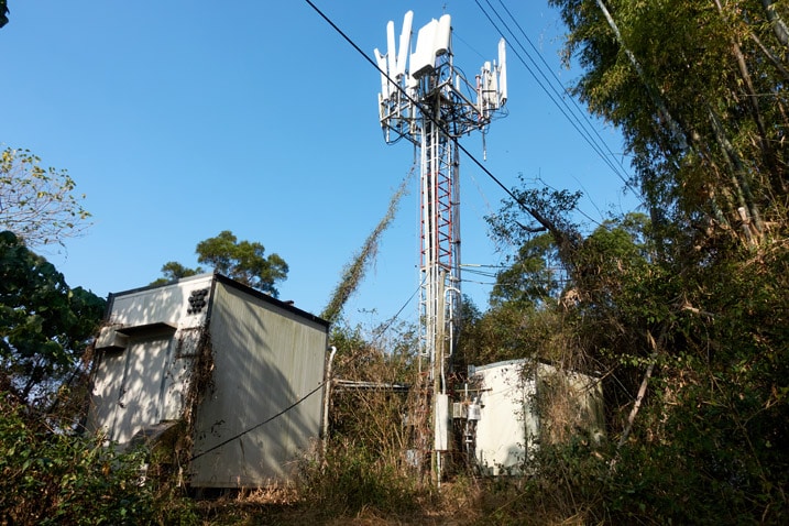 Cellphone tower and supporting equipment nearby - blue sky
