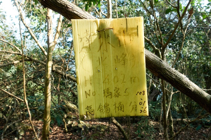Yellow sign with Chinese writing attached to a tree