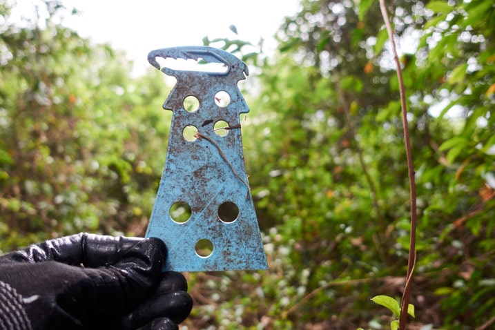 Blue plastic object possibly meant for farming - black gloved hand holding it