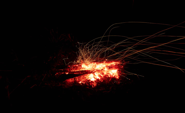 Campfire with sparks flying to the right - black all around fire