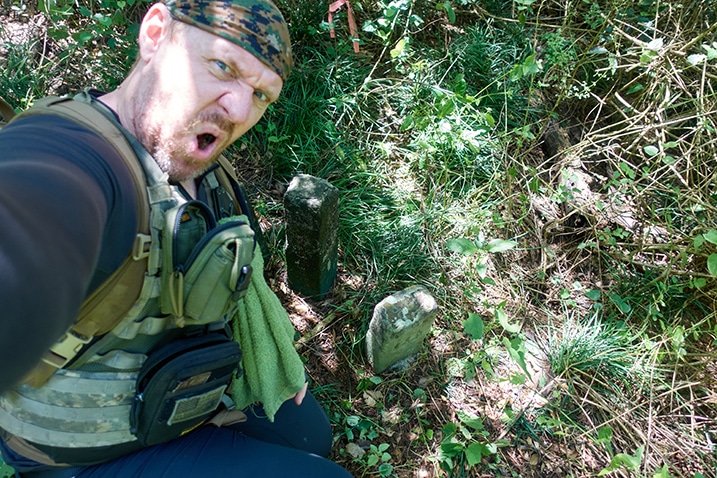 Man kneeling triumphantly near several stone markers in the ground